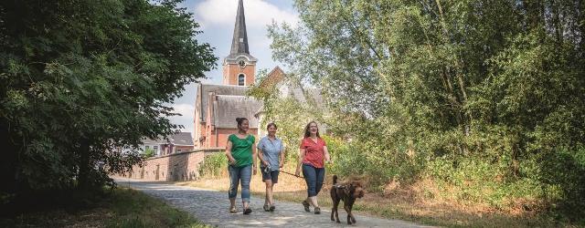 Wandelaars met hond aan de kerk van Hever