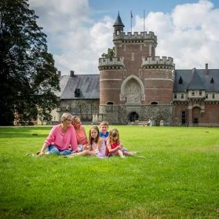 Vrouwen met kinderen zitten op grasperk vóór het kasteel van Gaasbeek