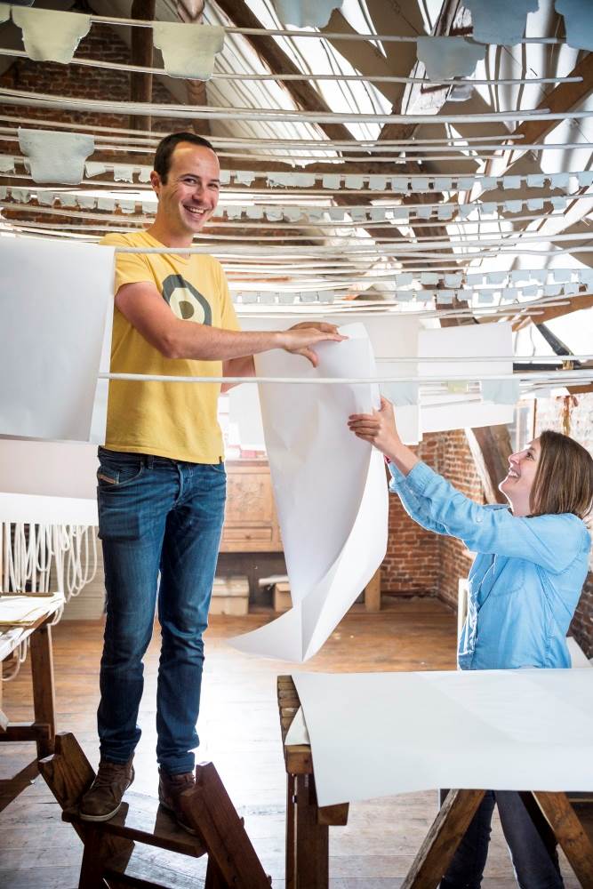 Twee mensen hangen papier aan de draad om te drogen